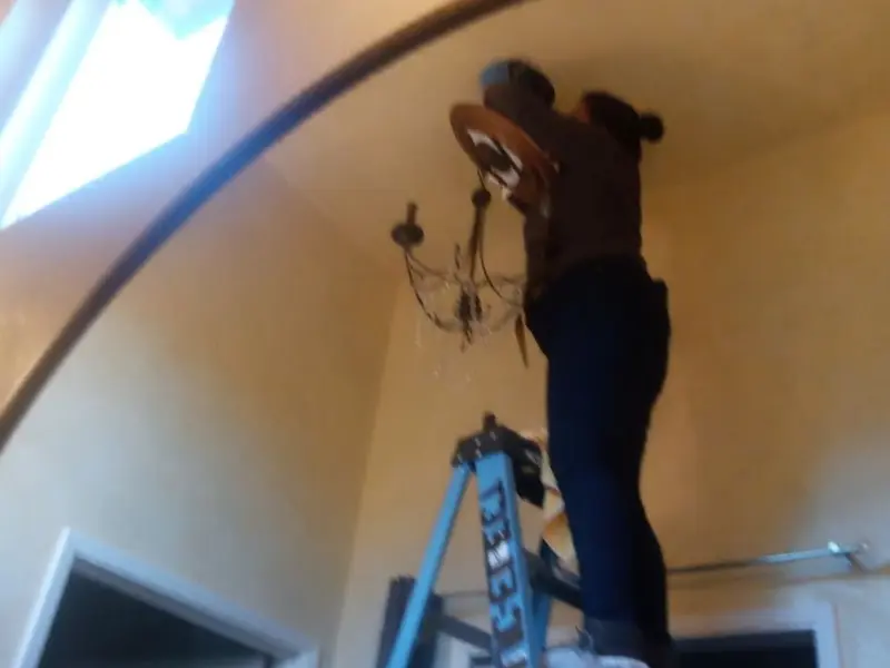 Electrician installing a chandelier in a Samoset residence